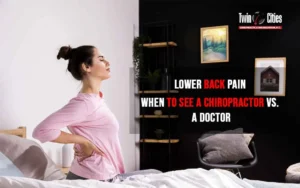 Woman holding her lower back in pain while getting out of bed, considering whether to see a chiropractor or medical doctor at Twin Cities Chiropractic & Rehabilitation.