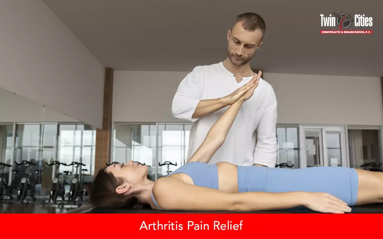 Chiropractor assisting a woman with an arm stretch during arthritis pain relief treatment at a chiropractic center.