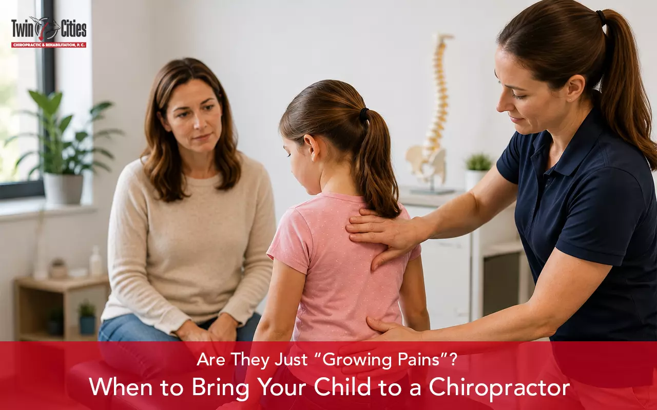 Chiropractor examining a child’s back with her mother present in a clinic