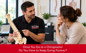 Chiropractor explaining spinal care to a woman while holding a spine model during a consultation.